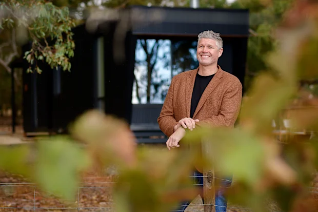 Michael Lamprell, Founder and CEO of CABN, outside a black off grid cabin